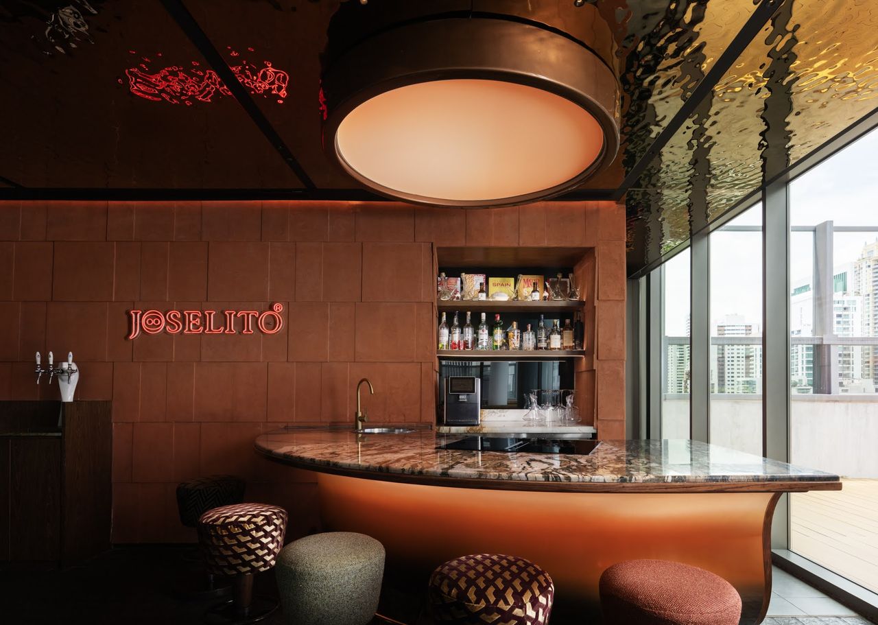 The curved copper bar at dusk, Spanish wine and glassware on the marble counter