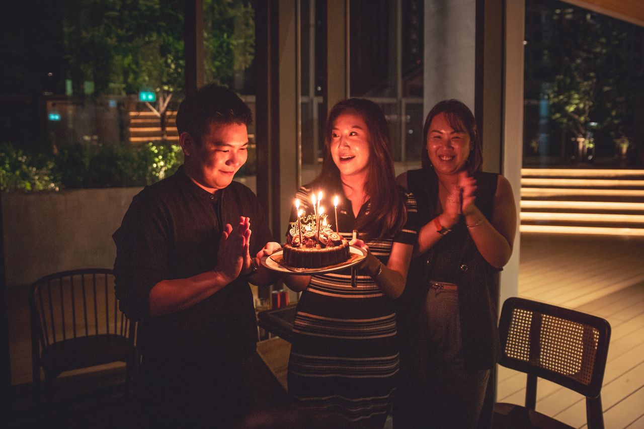Guests on the night terrace with a candle-topped celebration cake